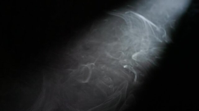 Light beams streaming through a skylight in a central Oregon lava tube cave, illuminating swirling mist