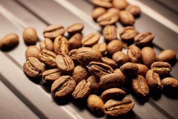 Close-up of roasted coffee beans on a black iron surface.