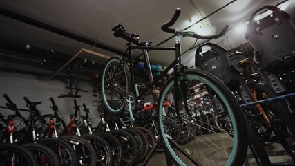 Modern bicycle on stand in local bike shop interior, various bicycles, parts and gear visible in background