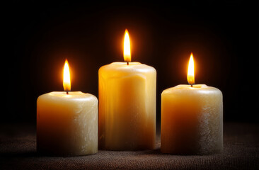 Three burning candles flame wax warm glow dark background peaceful mood