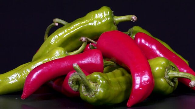 Close-up footage of red and green peppers on black background.