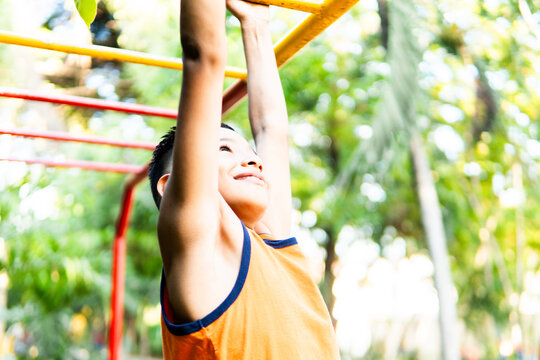 Happy boy playing on monkey bars at park - Powered by Adobe