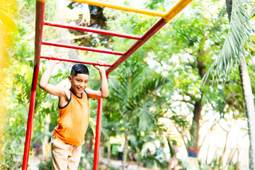 Hispanic elementary school student hanging on monkey bars smiling