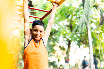 Happy hispanic boy playing on monkey bars outdoors