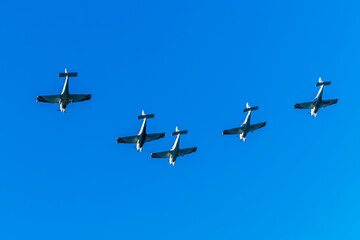 Group of aircraft planes in flight during airshow. Jets flying in the air. Airborne sport in thr sky with airplanes with blue background.