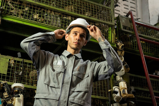 Technician worker standing and look at camera in garage scrap yard car workshop warehouse.