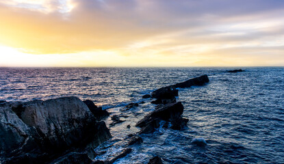 beautiful sea sunset among rocks and blue water vawes and amazing colorful cloudy evening sky on background. Sunrise morning scenery view of seascape with blue ocean.