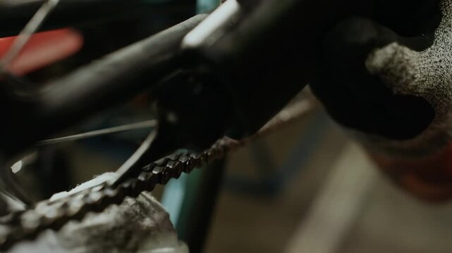 Close-up of unrecognizable repairman lubricating bicycle chain, applying small drops of oil onto each roller
