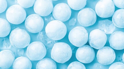Numerous small, round ice balls and crushed ice on a light blue background, creating a cool, frosty, and refreshing texture.