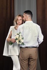 A wedding portrait of the newlyweds. The groom holds the bride's hand.	
