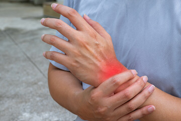 Person gripping painful wrist during outdoor workout. Red inflammation signals exercise-related injury. Copy space for medical or physiotherapy ads.