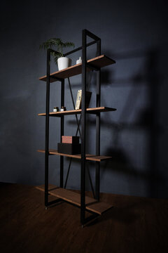 Loft-style interior with metal bookcase. Modern minimalist shelving with wooden shelves on a dark background