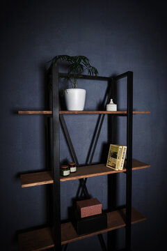 Loft-style interior with metal bookcase. Modern minimalist shelving with wooden shelves on a dark background