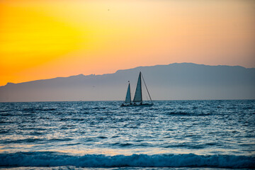 Fototapeta premium Evening sea with sailboat reflects soft light. Sunset sea with sailboat calms the traveler. Evening sea with sailboat fades into silence. Sunset sea with sailboat captures peaceful time.