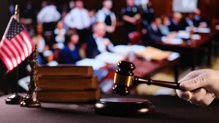 Judge in courtroom raises gavel before striking to announce decision. Wooden hammer with blurred audience symbolizes justice - Powered by Adobe