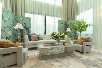 Interior of a luxurious sitting room with bay window sofas and coffee table. White and green tone of vast luxury living room.
