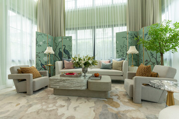 Interior of a luxurious sitting room with bay window sofas and coffee table. White and green tone of vast luxury living room.
