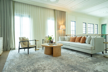 Interior of a luxurious sitting room with bay window sofas and coffee table. White and green tone of vast luxury living room.
