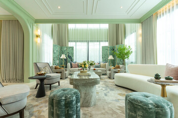 Interior of a luxurious sitting room with bay window sofas and coffee table. White and green tone of vast luxury living room.
