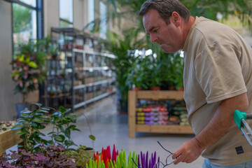 Mature man shopping for plants at a garden center, focusing on diverse flora for his home hobby