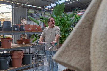 Man pushing shopping cart in a garden center, choosing new pots and plants for his home garden