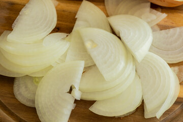 slicing onion on wooden cutting board close up
