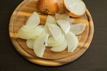 slicing onion on wooden cutting board close up