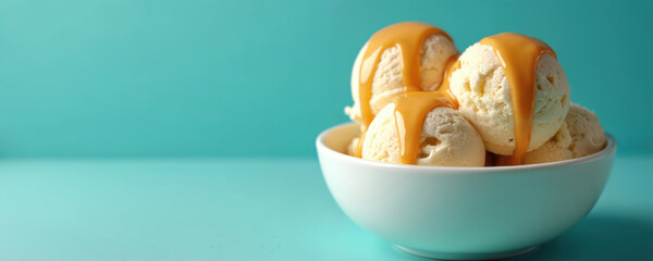 Scoops of vanilla ice cream are generously drizzled with sweet caramel sauce in a white bowl. This tempting dessert looks creamy and cold, perfect for a summer treat or sweet indulgence.