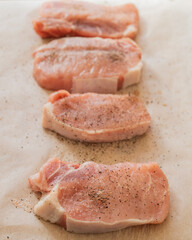 fresh pork chops seasoned with salt and pepper on parchment paper