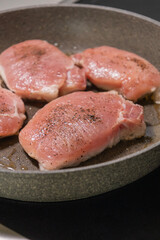seasoned raw pork chops in pan ready to cook