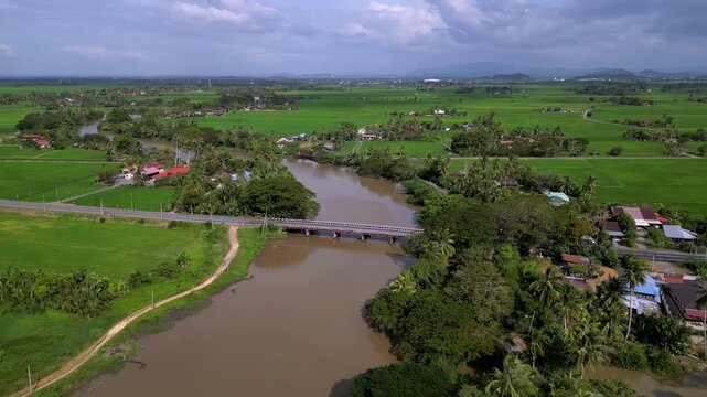 A river runs through a green field with a bridge over it. Aerial view Kuala Sala, Kedah