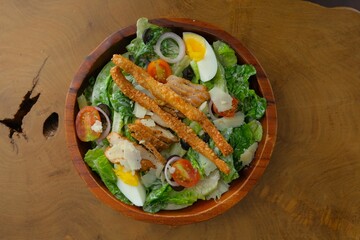 Caesar salad in wooden bowl . Served with cheese stick , grilled chicken and boiled egg. Healthy food, ideal for recipe, food blogger and menu for restaurant. Salad sayur