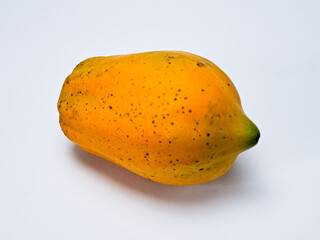 Ripe papaya fruit sits against a clean background showing a smooth, yellow and green skin.