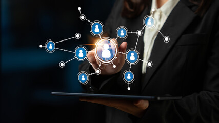 A business professional engages with digital technology to illustrate online networking and community connections in a darkened environment using visual icons. Tessel