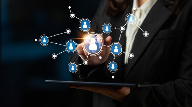 A business professional engages with digital technology to illustrate online networking and community connections in a darkened environment using visual icons. Tessel