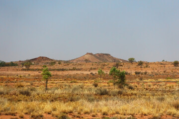 Small hills  and flat landscape in the savannah of the Northern Territory of Australia, with dry grass and small shrubs.