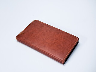 An aged leather journal with hand-stitched edges sits on a neutral background in soft lighting.