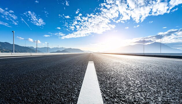 Empty Asphalt Highway Leading Towards Distant Mountains at Sunrise