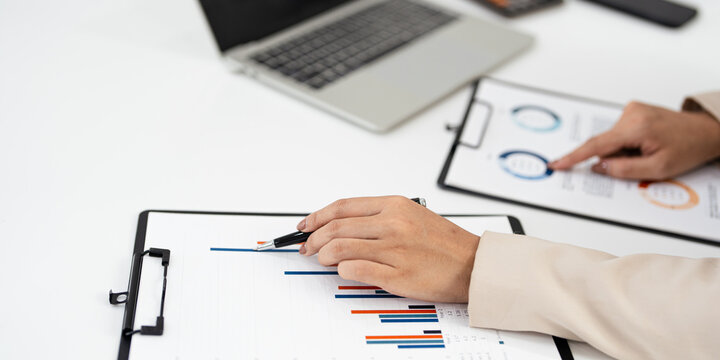 Close up hand of businesswoman hand pointing graphic chart with pen. reviweing Financial, account, statistics and business data concept.