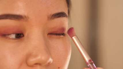 A young woman applies makeup in front of a mirror, focusing on her daily beauty and skincare routine. Elegant and natural look, perfect for beauty, lifestyle, and cosmetic content
