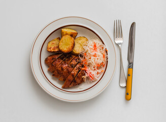 Delicious lunch - grilled turkey, baked potatoes, sauerkraut on a light background, top view