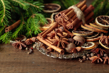 Various Christmas spices with dried citrus slices on silver tray.
