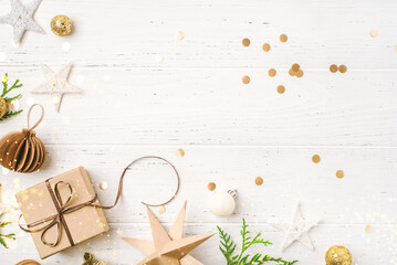 Festive Christmas background with gift box and Christmas decorations on white wooden table. Top view. Copy space for text.