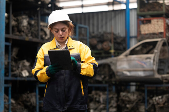 Hispanic female foreman worker standing holding tablet, checking inventory of auto parts and engine maintenance duties in factory.
 - Powered by Adobe