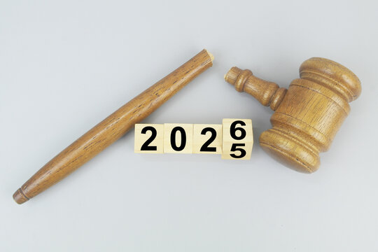 Broken wooden judge gavel and flipping numbers 2025 and 2026 on cubes. Lawlessness and injustice in new laws in 2026.