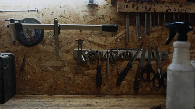 Design of workbench in garage or repair workshop with various tools and parts attached to chipboard wall