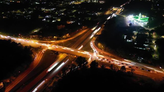 A city street with a large intersection. The street is lit up at night. There are many cars on the street. Aerial night view Larkin, johor
