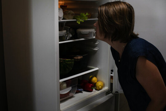 Mysterious late-night fridge foraging, Caucasian female, culinary curiosity, capturing elusive midnight snacks, International Fridge Cleaning Day ambiance