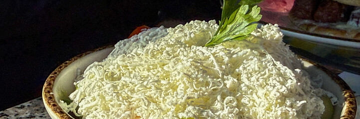 Fluffy mounds of grated cheese crown a rustic dish, evoking Balkan festivities and Mediterranean culinary nostalgia
