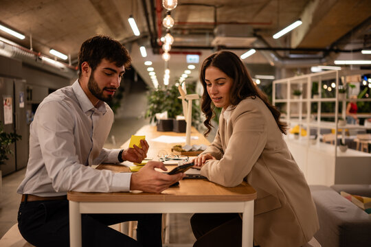 Business colleagues collaborating using smartphone in modern office